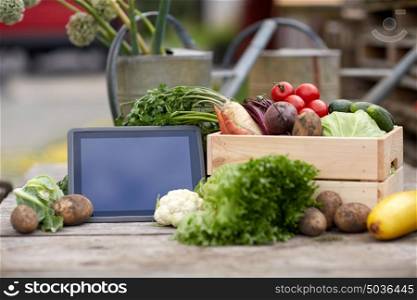harvest, food and agriculture concept - close up of vegetables with tablet pc computer on farm. close up of vegetables with tablet pc on farm