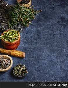 Harvest of medicinal plant. Bundle herbs and mortar with pestle on slate background.Copy space