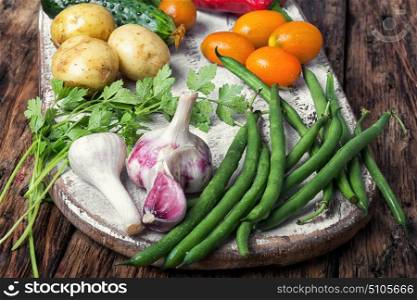 Harvest of summer vegetables. Fresh vegetables. Composition with assortment raw vegetables.Beans in pods, basil, orange tomato, pepper and potatoes