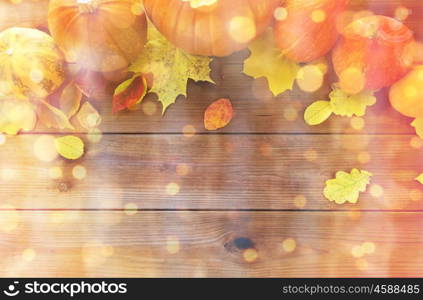 harvest, season, advertisement and autumn concept - close up of pumpkins and leaves on wooden table at home