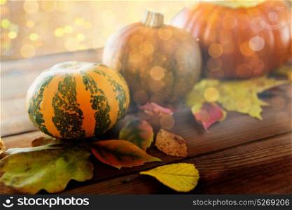 harvest, season, advertisement and autumn concept - close up of pumpkins and leaves on wooden table at home. close up of pumpkins on wooden table at home