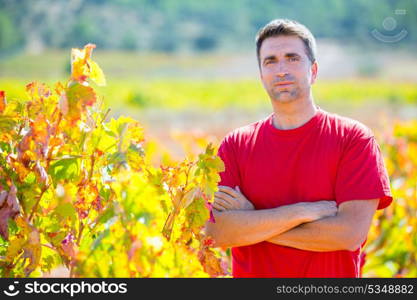 Harvester winemaker farmer proud of his vineyard in autumn golden red leaves at Mediterranean