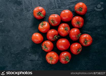 Harvesting ripe wet red tomatoes on dark background. Top view. Copy space. Organic fresh vegetables. Raw food. Clean eating concept