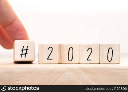 Hashtag 2020 concept, hand change wooden cubes close-up with white background close-up. Hashtag 2020 concept, hand change wooden cubes close-up with white background
