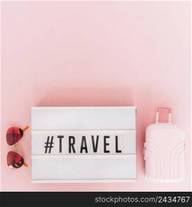 hashtag with travel text lightbox with sunglasses miniature travel bag pink background