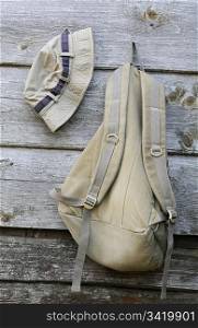 Hat and backpack of khaki color on the shabby wooden wall