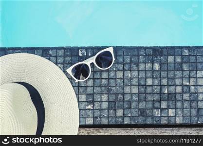 Hat and sunglass on luxury swimming pool tropical beach resort , summer concept