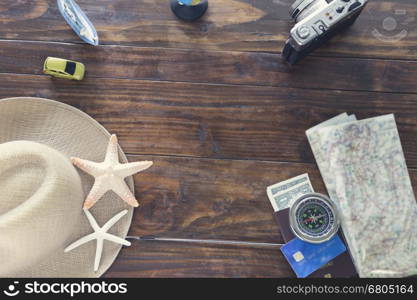 hat, compass, passport, credit card, banknote money, globe, camera, map, car ship and starfish figurine on wooden table for use as traveling concept (vintage tone and selected focus)