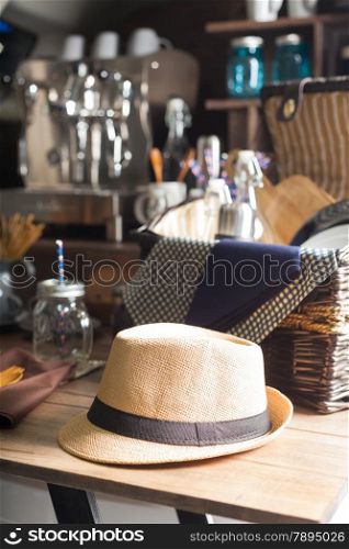 Hat resting on a wooden table. A picnic basket and a coffee maker in the background.