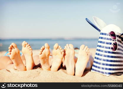 hats and summer concept - three women lying on the beach with straw hat, sunglasses and bag