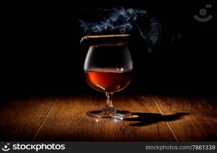Havana cigar on a wineglass of whiskey