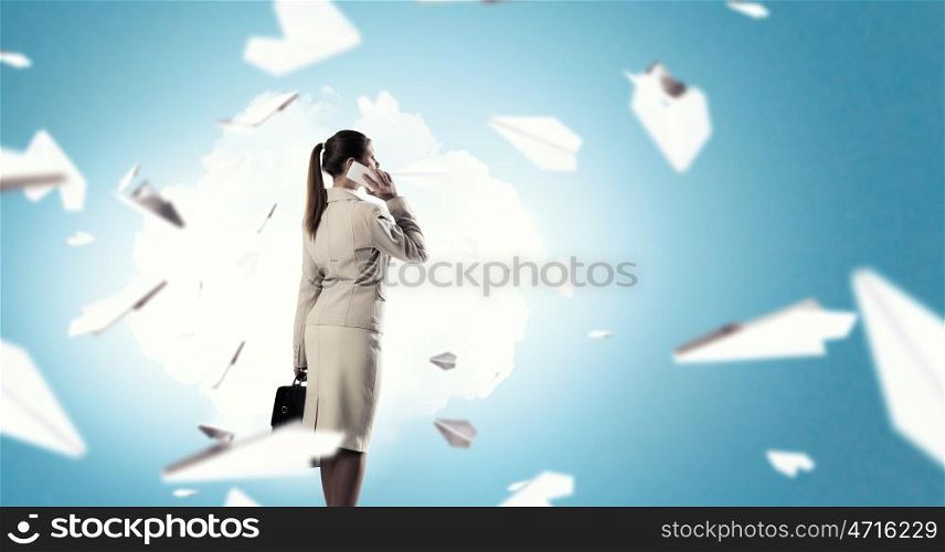 Having business talk mixed media. Successful businesswoman or entrepreneur talking on cellphone standing in modern office