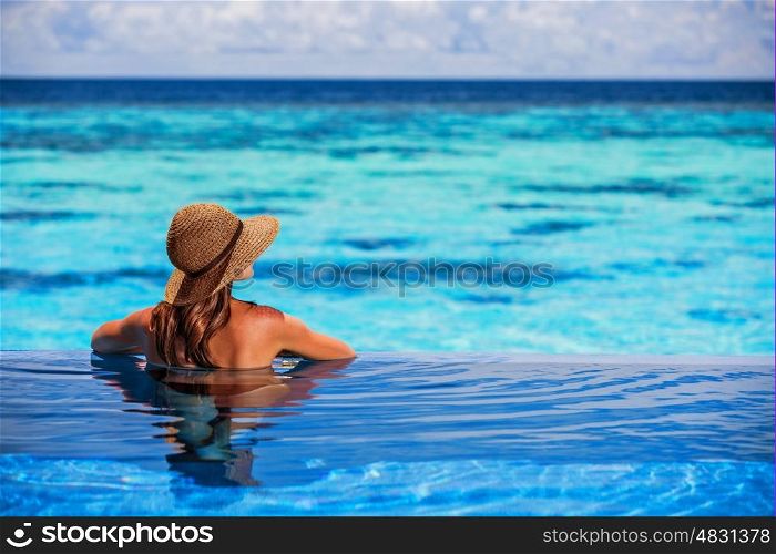 Having fun on beach resort, back side of sexy woman enjoying seascape from the pool, luxury summer vacation, travel and tourism concept