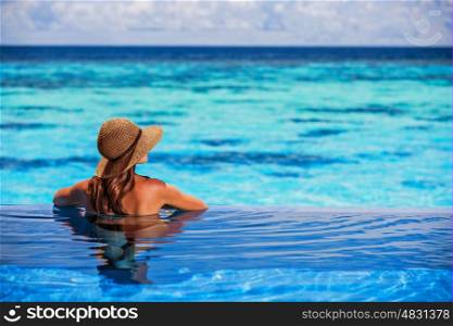 Having fun on beach resort, back side of sexy woman enjoying seascape from the pool, luxury summer vacation, travel and tourism concept