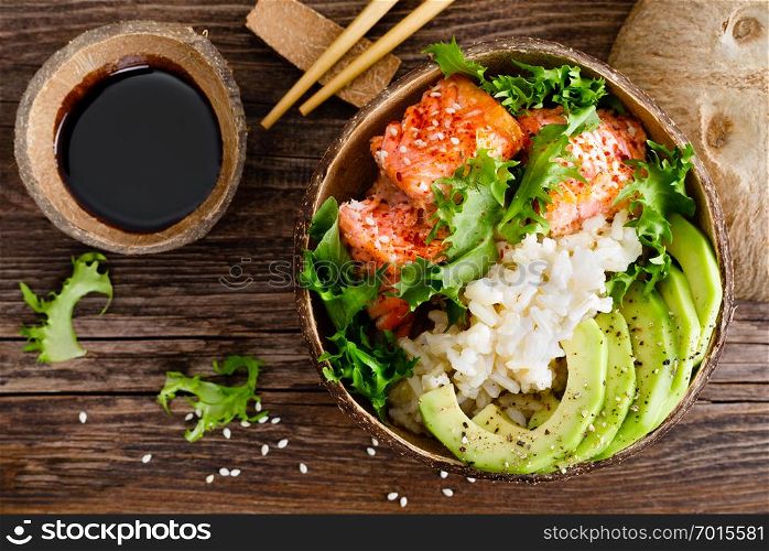Hawaiian poke coconut bowl with grilled salmon fish, rice and avocado. Healthy food. Top view