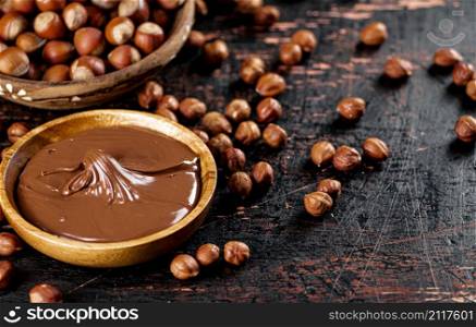 Hazelnut butter and inshell hazelnuts on the table in plates. Against a dark background. High quality photo. Hazelnut butter and inshell hazelnuts on the table in plates.
