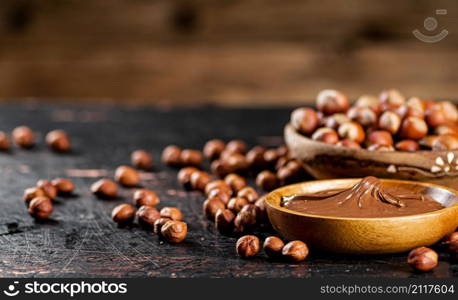Hazelnut butter in a plate on the table. On a wooden background. High quality photo. Hazelnut butter in a plate on the table.