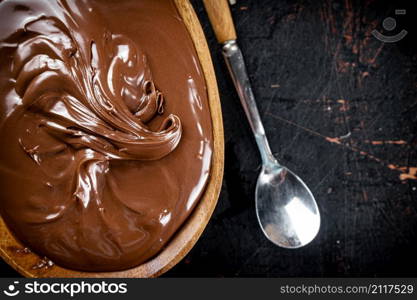 Hazelnut butter in a plate with a spoon. Against a dark background. Top view. High quality photo. Hazelnut butter in a plate with a spoon.