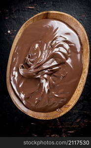 Hazelnut butter in a plate with a spoon. Against a dark background. Top view. High quality photo. Hazelnut butter in a plate with a spoon.