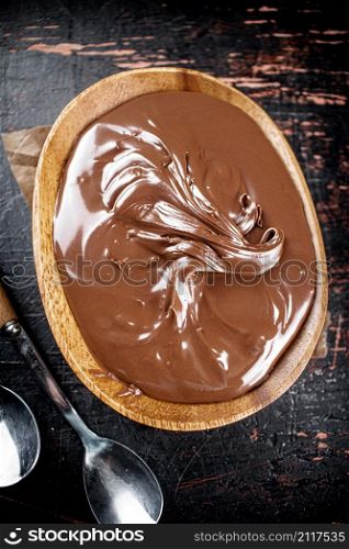 Hazelnut butter in a plate with a spoon. Against a dark background. Top view. High quality photo. Hazelnut butter in a plate with a spoon.