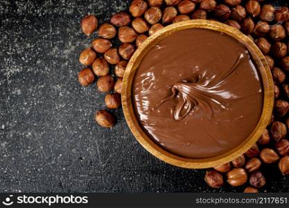 Hazelnut butter in a plate with peeled hazelnuts. On a black background. High quality photo. Hazelnut butter in a plate with peeled hazelnuts.