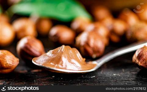 Hazelnut butter in a spoon on the table. On a rustic dark background. High quality photo. Hazelnut butter in a spoon on the table.