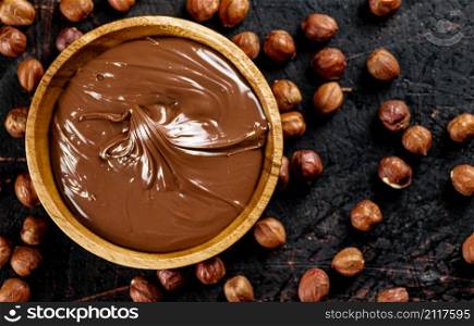 Hazelnut butter with peeled hazelnuts on the table. On a rustic dark background. High quality photo. Hazelnut butter with peeled hazelnuts on the table.