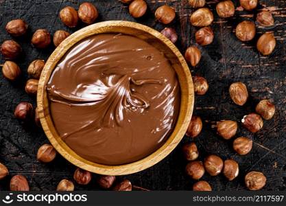 Hazelnut butter with peeled hazelnuts on the table. On a rustic dark background. High quality photo. Hazelnut butter with peeled hazelnuts on the table.