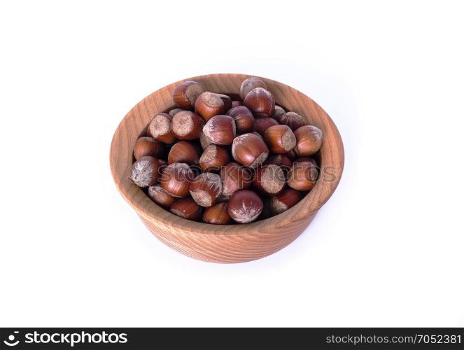 hazelnut in a shell in a brown wooden plate isolated on a white background, top view