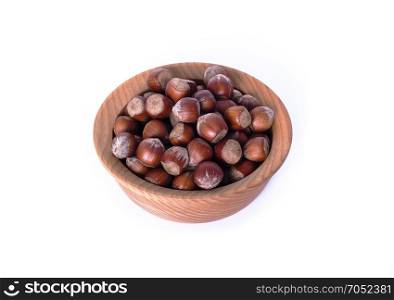 hazelnut in a shell in a brown wooden plate isolated on a white background, top view