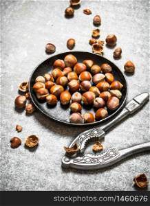 Hazelnuts and a Nutcracker in the old pan. On the stone table.. Hazelnuts and a Nutcracker in the old pan.
