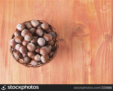 Hazelnuts in a basket on a wooden table. Hazelnuts in a basket on wooden background. The view from the top