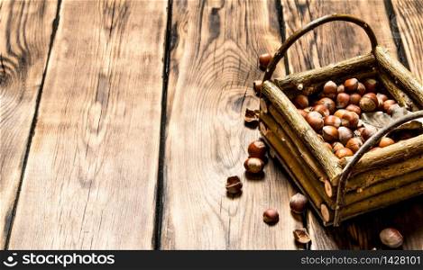 Hazelnuts in a basket with dry leaves. On wooden background.. Hazelnuts in a basket with dry leaves.