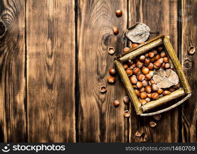 Hazelnuts in a basket with dry leaves. On wooden background.. Hazelnuts in a basket with dry leaves.