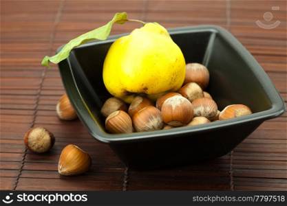 hazelnuts in a bowl and quinces on a bamboo mat
