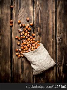 Hazelnuts in the old bag. On wooden background.. Hazelnuts in the old bag.