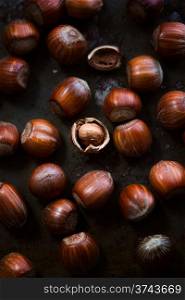 Hazelnuts on dark rusty background, the middle one is cracked
