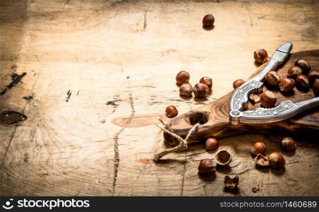 Hazelnuts with Nutcracker on the Board. On a wooden table.. Hazelnuts with Nutcracker on the Board.