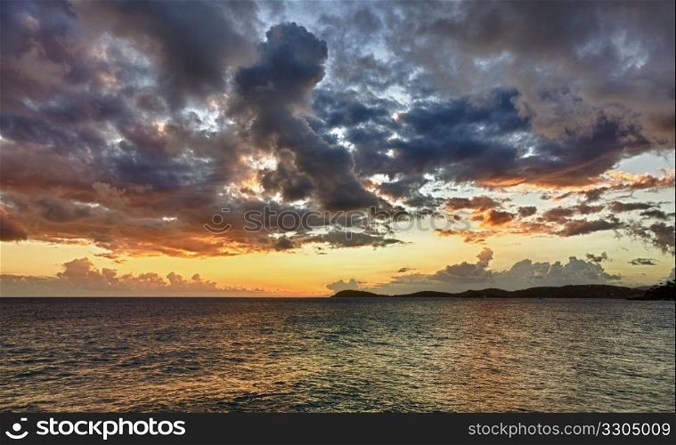 HDR impression of a sunset over the ocean with a distant island on the horizon