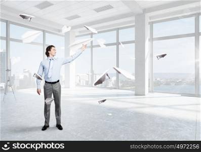 He doesn&rsquo;t take life too seriously. Young businessman in modern office with paper plane in hand