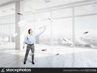 He doesn&rsquo;t take life too seriously. Young businessman in modern office with paper plane in hand
