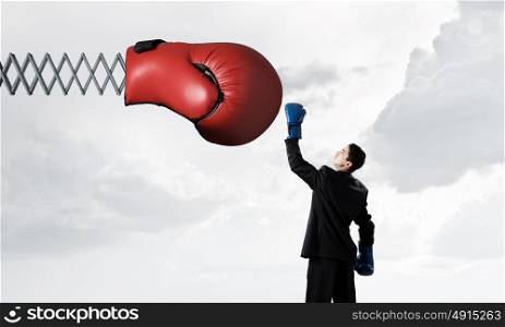 He fights for success. Determined businessman in boxing gloves fighting with glove on spring