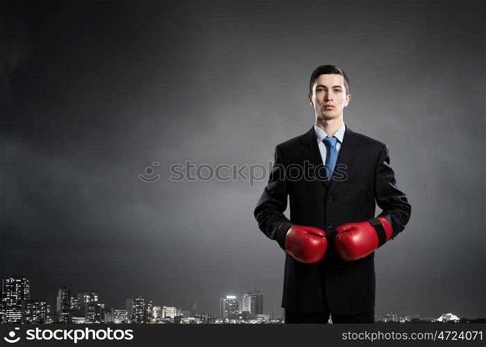 He fights for success. Determined businessman in suit and boxing gloves