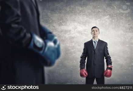 He fights for success. Determined businessman in suit and boxing gloves