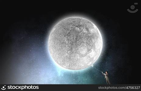 He gets what he wants. Young businessman in hat who obtains moon with rope