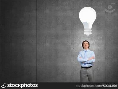 He has got bright idea . Confident businessman with arms crossed and bulb above head