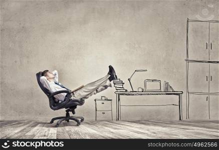 He is bosy and relaxed. Smiling businessman sitting in chair with legs on table