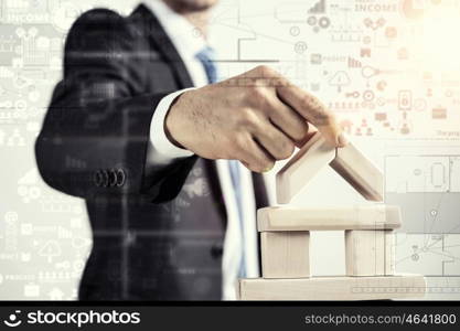 He is building his business. Close view of businessman making pyramid with empty wooden cubes