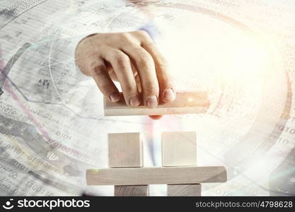 He is building his business. Close view of businessman making pyramid with empty wooden cubes