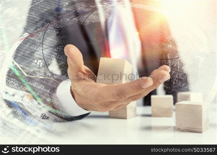 He is building his business. Close view of businessman making pyramid with empty wooden cubes